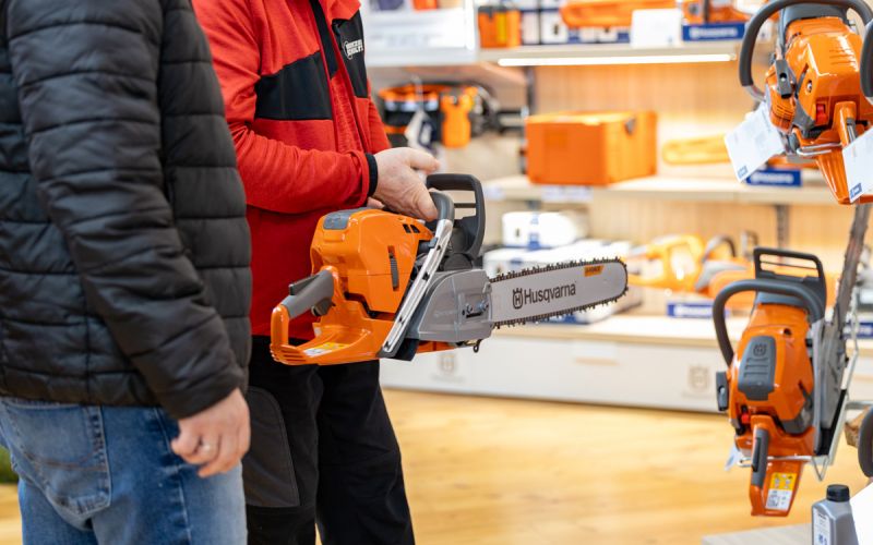 Beratung im Fachmarkt von Werkzeug Schultze: Mitarbeiter erklärt einem Kunden eine Motorsäge aus dem Forst- und Gartentechnik-Sortiment.