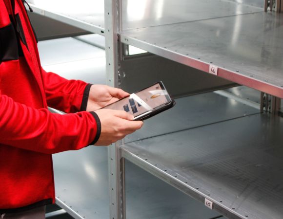 Digitale Prüfung von Regalanlagen – Mitarbeiter kontrolliert Fachböden per Tablet für sichere und normgerechte Lagerlösungen.