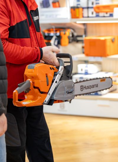 Beratung im Fachmarkt von Werkzeug Schultze: Mitarbeiter erklärt einem Kunden eine Motorsäge aus dem Forst- und Gartentechnik-Sortiment.