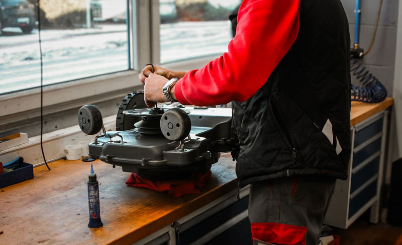 Wartung eines Mähroboters im Winterservice auf der Werkbank durch Servicetechniker in der Werkstatt.