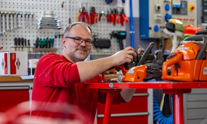 Servicetechniker wartet Husqvarna Motorsäge in Werkstatt – fachgerechter Service und Reparatur von Gartengeräten.