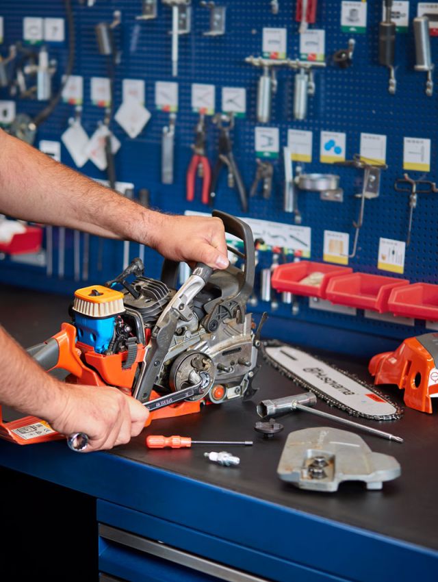 Reparatur einer Motorsäge in der Werkstatt von Werkzeug Schultze – Fachkraft wartet und justiert das Gerät professionell.
